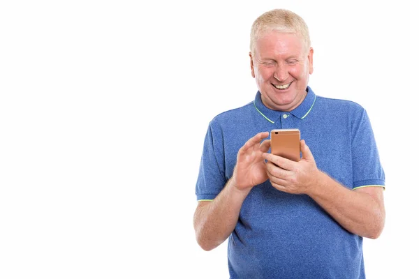 Studio shot van gelukkig volwassen man die lacht tijdens het gebruik van mobiele telefoon — Stockfoto