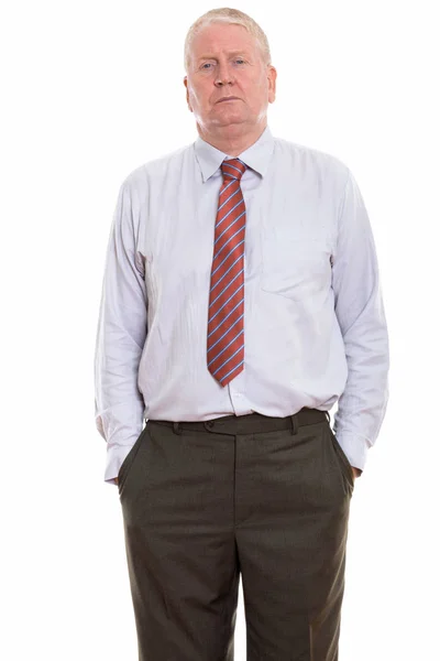 Studio shot of mature businessman standing with hands on pockets — Stock Photo, Image