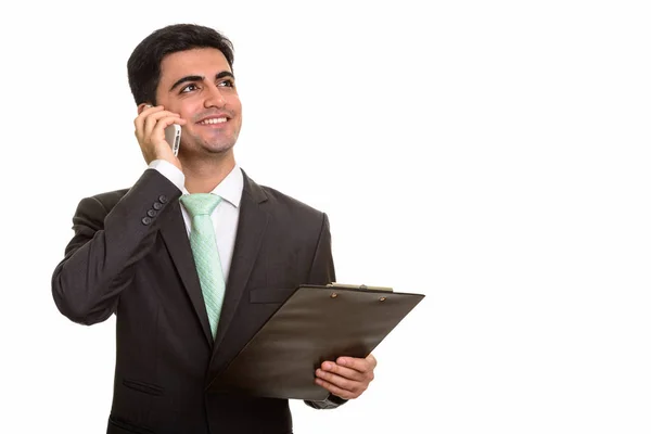 Молодой счастливый персидский бизнесмен разговаривает по мобильному телефону, пока хо — стоковое фото