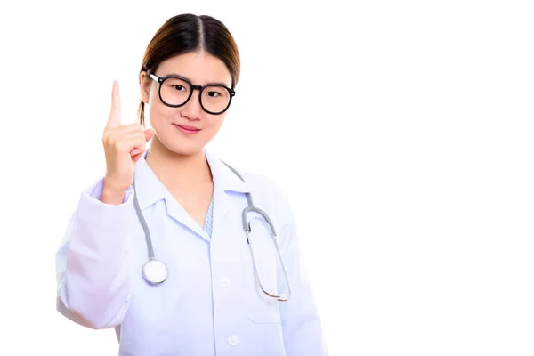 Студийный снимок молодой красивой азиатки-врача, указывающей пальцем — стоковое фото