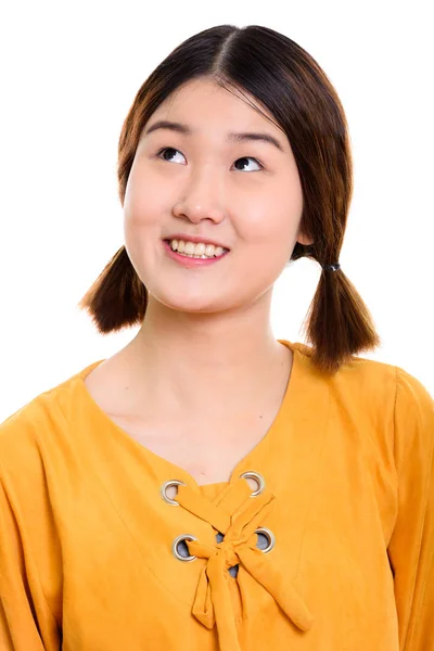 Rosto da jovem mulher asiática feliz sorrindo enquanto pensa — Fotografia de Stock