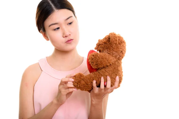 Young beautiful Asian woman holding and looking at teddy bear wi — Stock Photo, Image