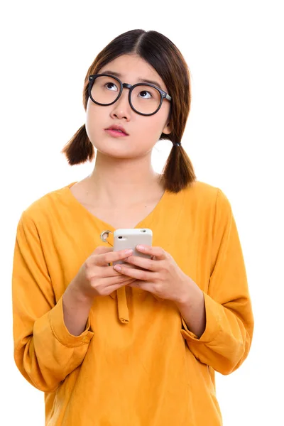 Joven mujer asiática reflexiva sosteniendo el teléfono móvil —  Fotos de Stock