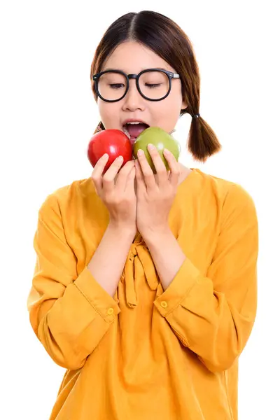Stúdió lövés a fiatal gyönyörű ázsiai nő étkezési piros alma és — Stock Fotó