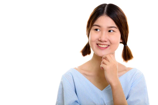 Studio shot van jong gelukkig aziatisch vrouw glimlachen terwijl denken — Stockfoto