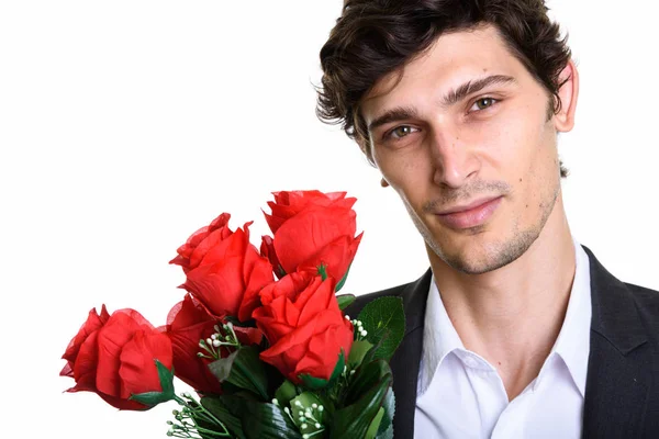 Närbild av ung stilig affärsman som håller röda rosor — Stockfoto