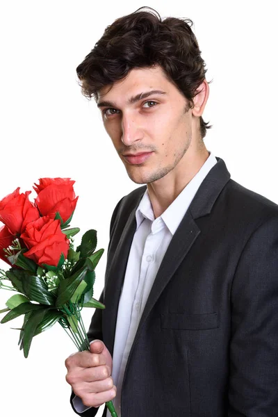 Studio bild av ung stilig affärsman som håller röda rosor — Stockfoto