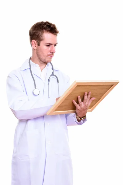 Студійний знімок лікаря-чоловіка, який читає на дерев'яній дошці — стокове фото