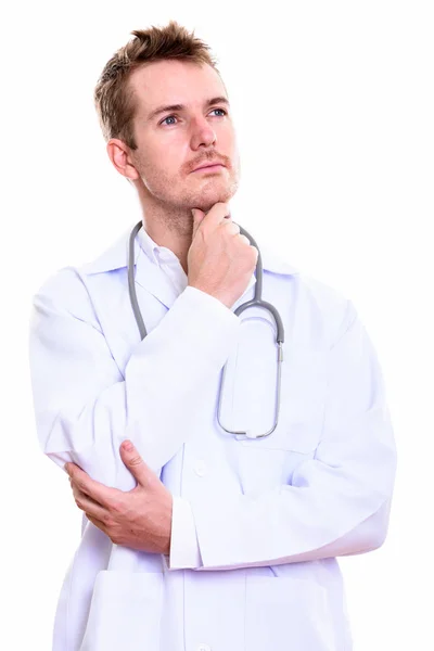 Studio shot of man doctor thinking while looking up — Stock Photo, Image