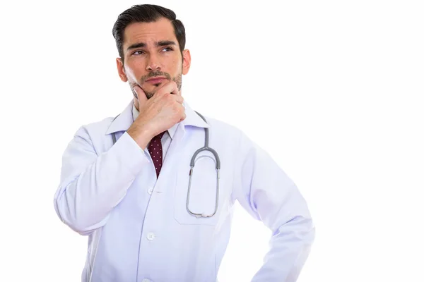 Studio shot of young handsome man doctor thinking while looking — Stock Photo, Image