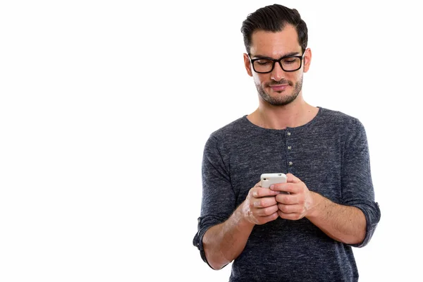 Studio shot van de knappe jongeman met behulp van mobiele telefoon tijdens weari — Stockfoto