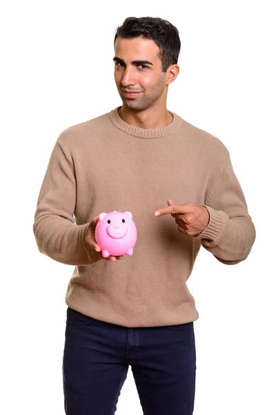 Young handsome Caucasian man holding piggy bank and pointing fin — Stock Photo, Image