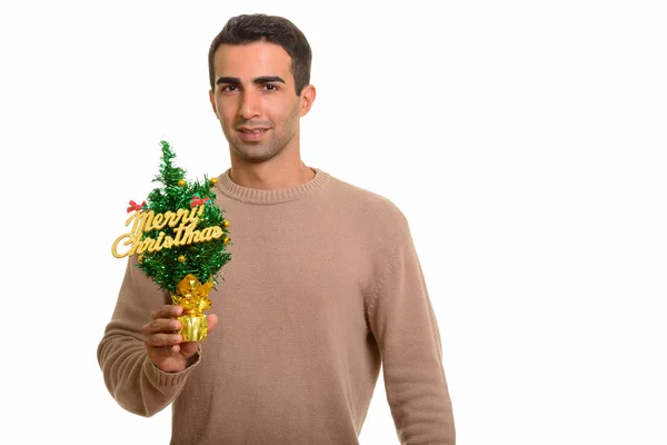 Joven hombre feliz sosteniendo Feliz árbol de Navidad — Foto de Stock