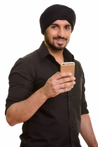 Young happy Indian Sikh holding mobile phone — Stock Photo, Image