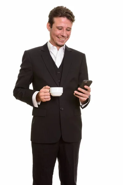 Empresário caucasiano feliz usando telefone celular enquanto segurando cof — Fotografia de Stock