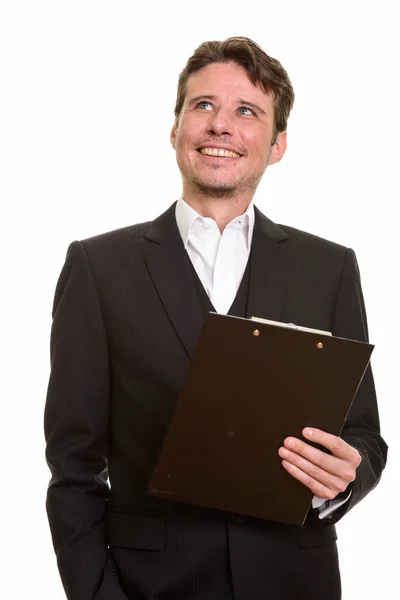 Happy Caucasian businessman thinking while holding clipboard — Stock Photo, Image