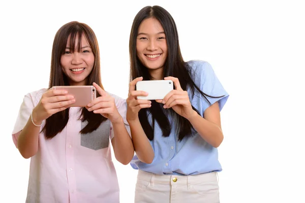 Two young happy Asian teenage girls smiling and taking picture w — Stock Photo, Image