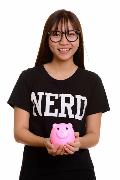 Jonge gelukkig Aziatische nerd tienermeisje glimlachend en houden piggy ba — Stockfoto