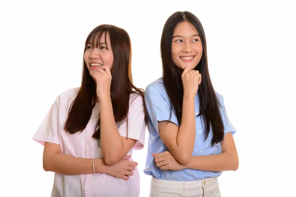Two young happy Asian teenage girls smiling and thinking togethe Stock Picture