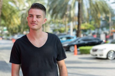Park l düşünürken gülümseyen mutlu yakışıklı delikanlı