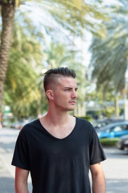 Genç yakışıklı adam park yerinde durup düşünürken