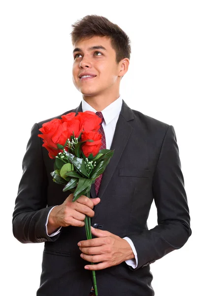 Pensativo jovem empresário feliz sorrindo enquanto segurando ros vermelhos — Fotografia de Stock