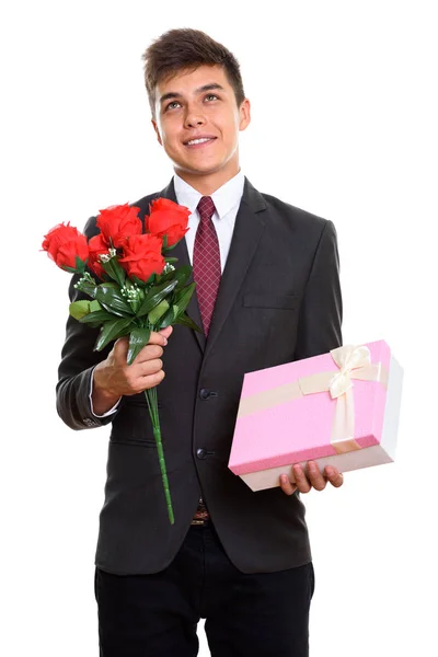 Nachdenklicher junger glücklicher Geschäftsmann lächelt, während er rote Rosen in der Hand hält — Stockfoto