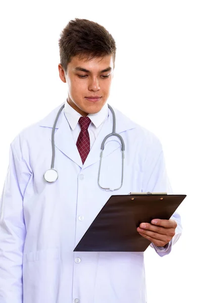 Studio shot of young handsome man doctor reading on clipboard — Stock Photo, Image