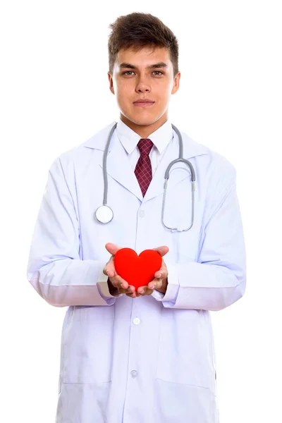 Studio shot of young handsome man doctor holding red heart with — Stock Photo, Image