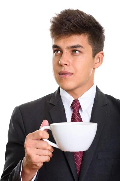 Joven hombre de negocios guapo sosteniendo la taza de café mientras piensa — Foto de Stock