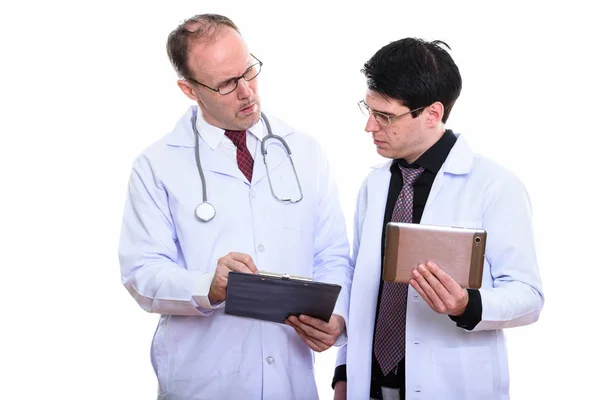 Ältere Mann Arzt hält Klemmbrett mit jungen Mann Arzt holdin — Stockfoto