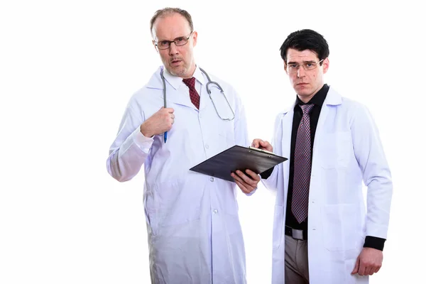 Maduro hombre doctor y joven hombre doctor holding portapapeles mientras b — Foto de Stock