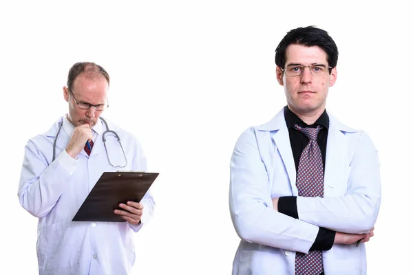 Joven doctor con los brazos cruzados y hombre maduro médico leyendo —  Fotos de Stock