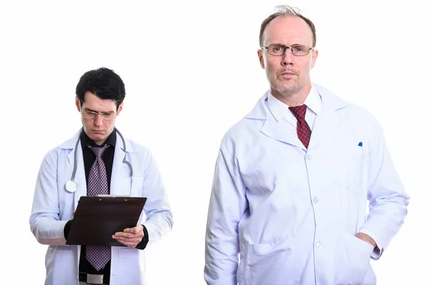 Mature homme médecin avec jeune homme médecin écriture sur presse-papiers — Photo