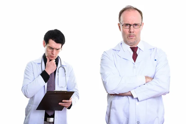腕を組んで中年の男性医師と若い男の医者を読んで — ストック写真