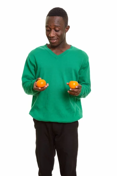 Jovem homem africano feliz sorrindo e segurando duas laranjas — Fotografia de Stock