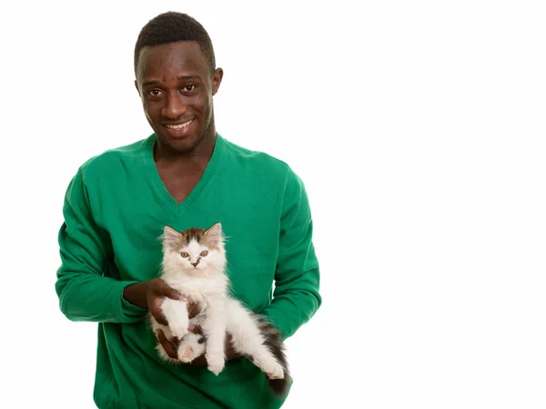 Genç mutlu Afrikalı adam gülümsüyor ve sevimli bir kedi tutuyor. — Stok fotoğraf