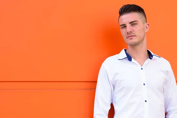 Junger schöner Mann gegen orangefarbene Betonwand — Stockfoto