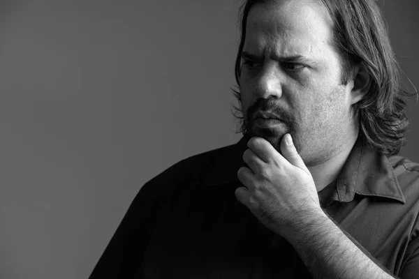 Close up of fat Caucasian man thinking in the dark in black and — Stock Photo, Image