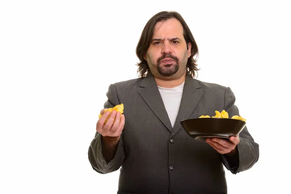 Een dikke blanke zakenman met een mond vol chips. — Stockfoto