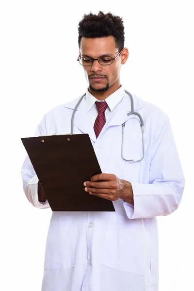Studio shot of young African man doctor reading on clipboard — Stock Photo, Image