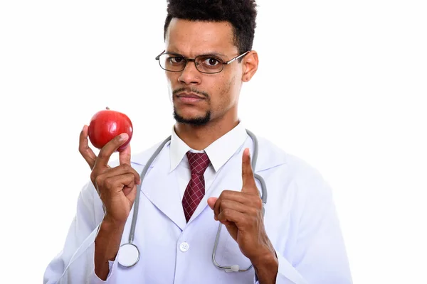 Joven africano médico sosteniendo manzana roja mientras señala con el dedo — Foto de Stock