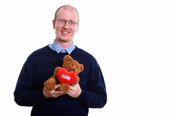 Feliz hombre sonriendo mientras sostiene oso de peluche con el corazón y el amor s —  Fotos de Stock