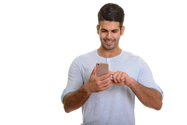 Joven feliz hombre persa sonriendo mientras usa el teléfono móvil —  Fotos de Stock