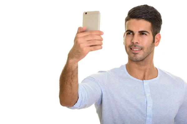 Jeune homme heureux persan souriant et prendre selfie avec mobile ph — Photo