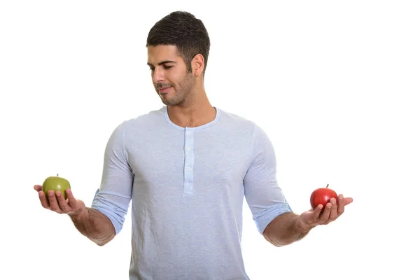 Joven hombre persa guapo elegir entre manzana roja y verde — Foto de Stock
