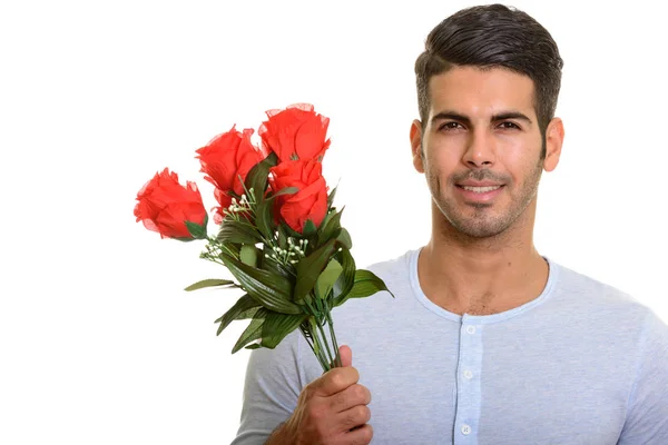 Joven hombre persa feliz sonriendo mientras sostiene rosas rojas listo fo — Foto de Stock