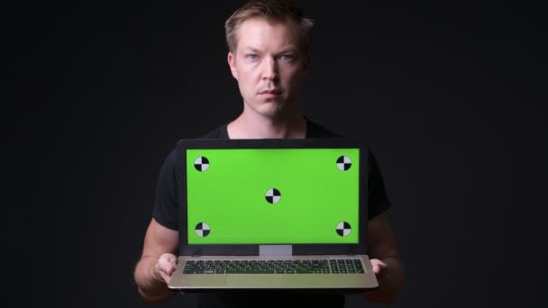 Joven hombre guapo utilizando el ordenador portátil con pantalla verde croma clave — Vídeos de Stock