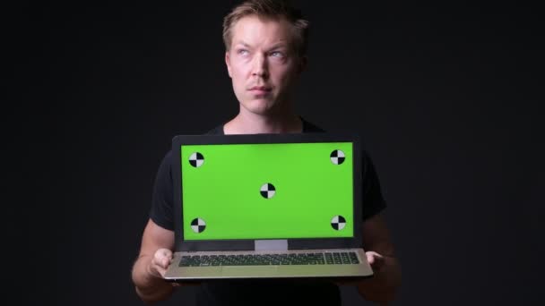 Mladý pohledný muž pomocí přenosného počítače s zelenou klíčování chroma — Stock video