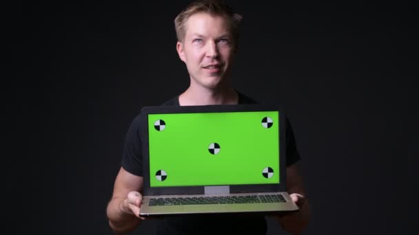 Jovem homem bonito usando laptop com chave de croma de tela verde — Vídeo de Stock